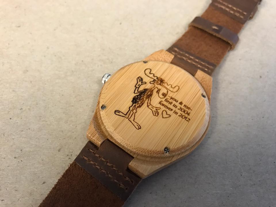 The back of a watch dispalys a laser engraved design of a moose with a quote: "You and me. First in 2004. Forever in 2012."